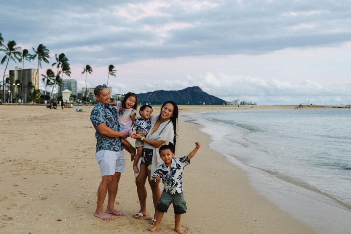 Kayla, her husband and their three kids on the beach smiling and having fun together